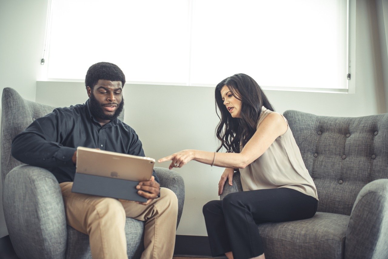 A man with a laptop and a woman sitting in two chairs.