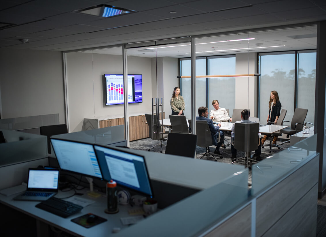 Office view looking into a glass conference room with a Jones meeting taking place